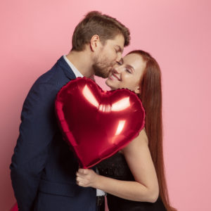 homme qui embrasse sa femme qui tient un ballon coeur pour la saint valentin